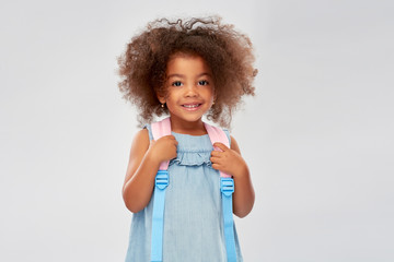 childhood, school and education concept - happy little african american girl with backpack over grey background