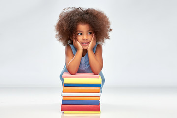 childhood, school and education concept - happy smiling little african american girl with pile of...