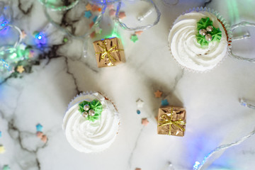 Obraz na płótnie Canvas New Year's sweets on a marble table. Christmas cupcakes decorated with mastic and cream