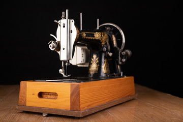 Old sewing machine on a dark table. An antique device for small housework.