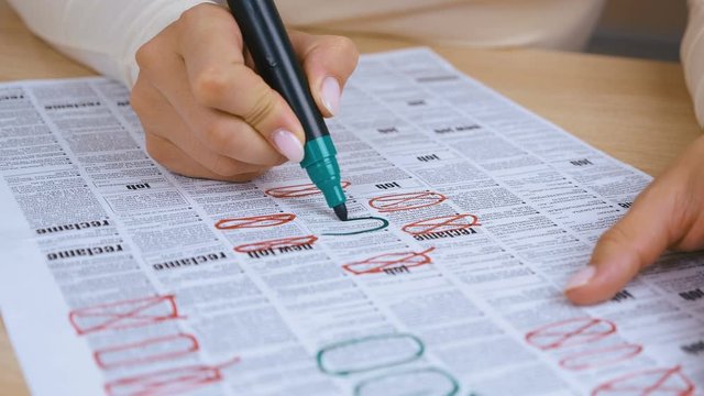 woman Looking for Job in a Newspaper and Marking Advertisement Using green Pencil. 4K