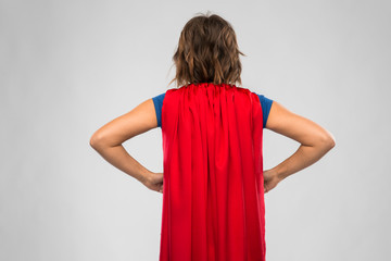 women's power and people concept - back view of young woman in red superhero cape over grey...