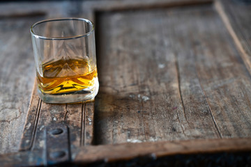 Whisky glass in sunny light on a special wooden old shabby table