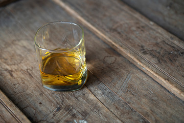 Close up of beautiful glass with golden whisky on a rustic wooden table in used look