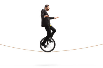 Excited young businessman riding a unicycle on a rope © Ljupco Smokovski