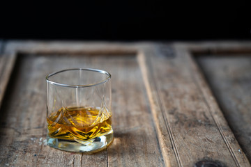 Glass of golden bourbon on an old rustic used wooden table