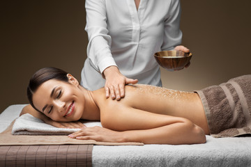 wellness, beauty and relaxation concept - beautiful young woman having salt massage at spa