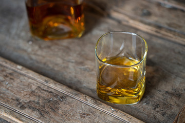 Shabby used wooden table with whisky glass from above