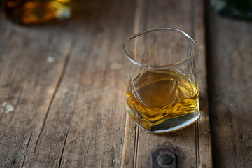 Glass of bourbon on an old used barrel 