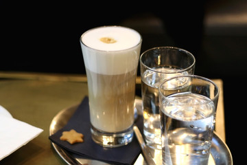Cappuccino, water and cookie in a cafe. Selective focus.