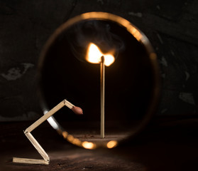Broken match is against the mirror and the reflection shows a whole standing burning stick