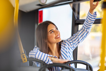Portrait of a woman inside a bus. Young woman taking bus to work. Woman riding in a bus and looking...