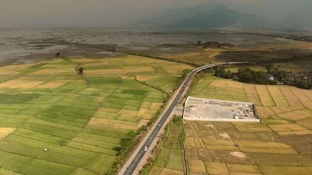 Aerial footage bird view of bypass highway road in Ambarawa city, Central Java, Indonesia with foggy volcano background