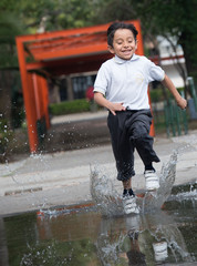 niño corriendo entre el agua salpicando y sonriendo 
