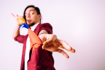 Young magician playing with colorful scarves, deep red, isolated on white background studio.