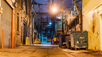 Fototapeta na wymiar Dark and scary vintage cobblestone brick city alley at night in Vancouver, British Columbia, Canada.