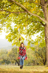 Beautiful young woman on a swing outdoors