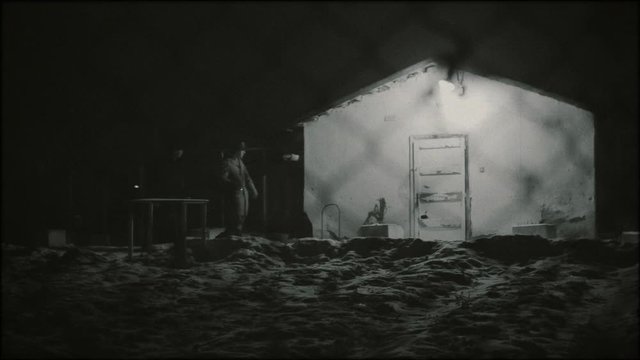 Barrack and wire fence and two anonymous silhouette. Communism concept