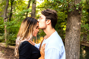 Fototapeta premium Young couple give their first kiss in a park at sunset, concept of falling in love.