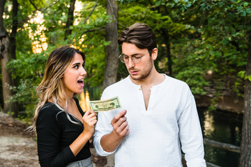 Woman steals a dollar bill from a man's hand.