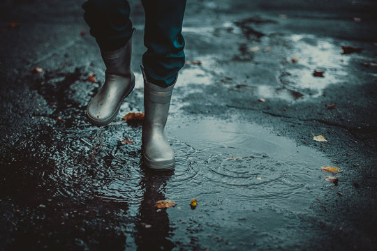 Close-up Boy Feeling Protected In His Grey Rubber Boots Walking On The Puddle