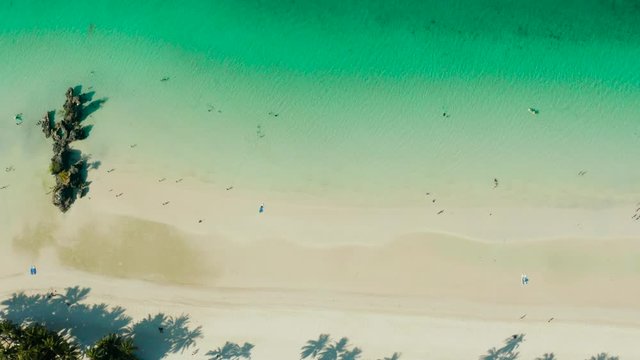 White sandy beach with tourists and azure water of the lagoon,copy space for text, top view. Ocean with waves and tropical beach. Summer and travel vacation concept