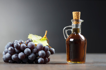 Glass bottle of organic black grape balsamic vinegar made from fermented fresh grapes. Healthy organic food black fruit, selective focus