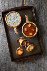 Two fresh homemade bowls of Clam Chowder and Tomato Soup with Garlic Toast on a metal baking sheet.