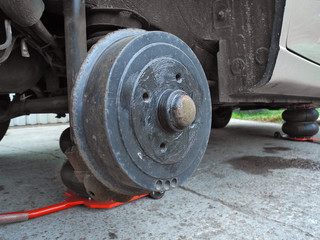 Car on tire mounting with removed wheel  on pneumatic jack. Wheel hub closeup. Seasonal tire change. Breakdown wheel. Car service concept. 