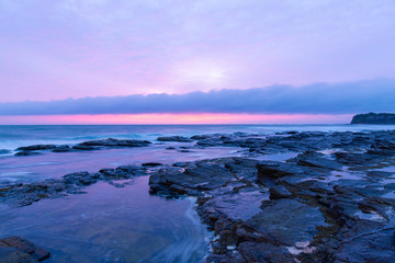 Rocky coastline under the overcast sunrise light.