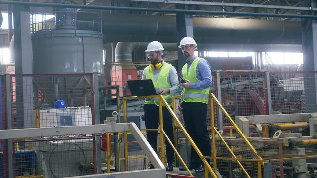 Two engineers check working machines at a brick factory.
