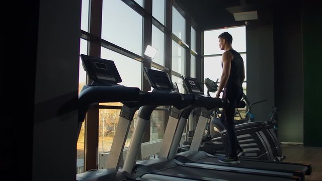 Young athletic men and women exercising and walk on treadmill in sport gym.