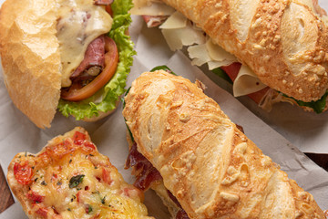 Set of different sandwiches with cheese, salad of letucce and tomato on wooden background