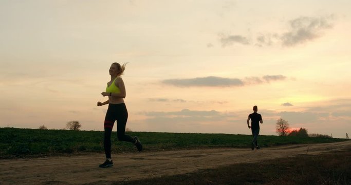 A man and a girl are clapping each other hand while running in autumn weather 4K