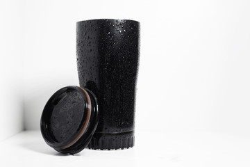 Black thermal mug for hot liquid with lid, on white background.