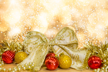 Background christmas or new year. Christmas decorations in gold and red balls and gold gift bow with tree decorations. Light bokeh background.