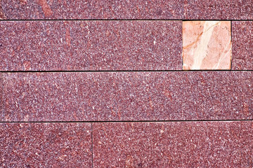 Spotted burgundy red stone surface with a lighter offset square area, empty surface for use in...