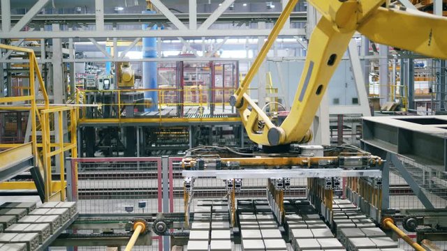 Automated, robotic machine moves bricks from a working conveyor.
