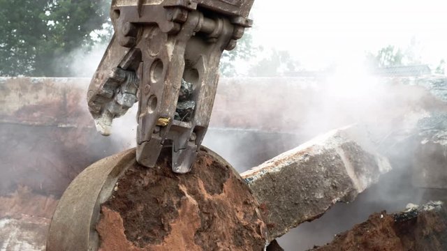 Slow Motion Shot of a Demolition Excavator Crushing a Concrete Cylinder in the Middle of Rubble and Debris on a Construction Site