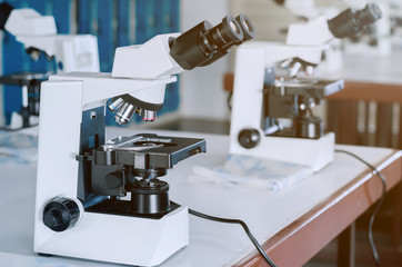 Microscope with micro plate on white table in laboratory setting for research and learning