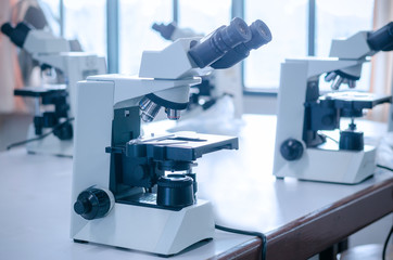 Microscope with micro plate on white table in laboratory setting for research and learning