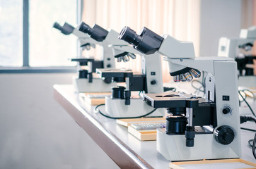 Row of Microscope with micro plate on white table in laboratory setting for research and learning