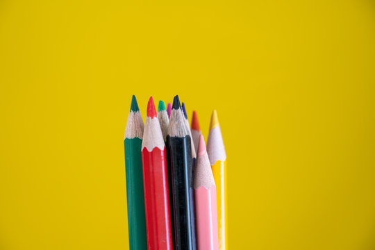 Colorful drawing pencils on yellow background