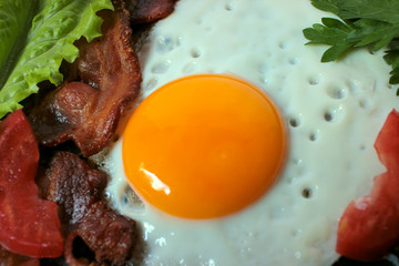 Fried eggs, traditional rustic breakfast, fried eggs, roasted bacon, sausage for breakfast on a wooden table background.  Healthy food
