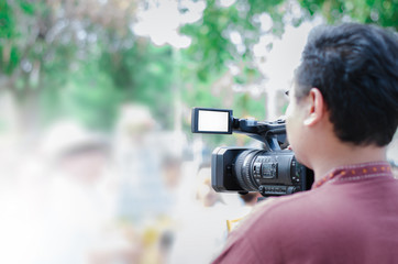 Professional video man hand holding Video camera operator camcorder working with his equipment outdoor with blurred background,copyspace