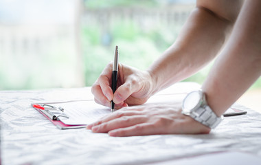 business man' s hand signing document paper ,selective focus on hand holding pen with copy space