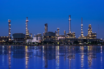 Obraz na płótnie Canvas Oil and gas refinery plant area near the river at twilight, sunset time