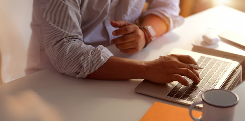 Close-up view of professional businessman typing on laptop computer while working on his project