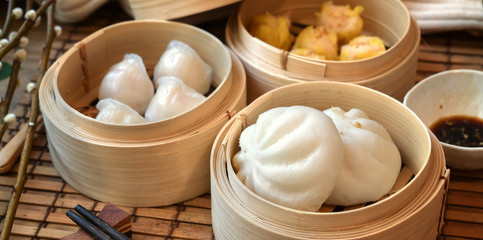 Chinese steamed dumpling and steamed pork bun in a bamboo steamer with chopstick