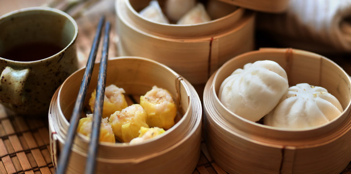 Chinese steamed dumpling and steamed pork bun in a bamboo steamer with chopstick